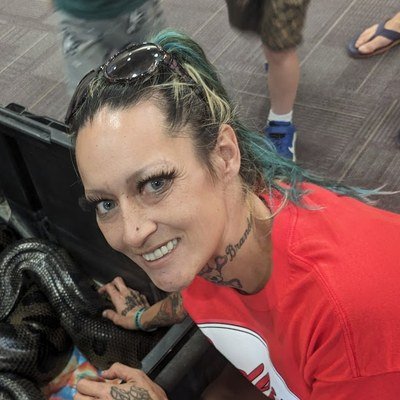Shiann Bowman smiling while helping restrain a large snake at a reptile rescue event